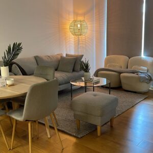 Customer apartment with a grey sofa and round ottoman